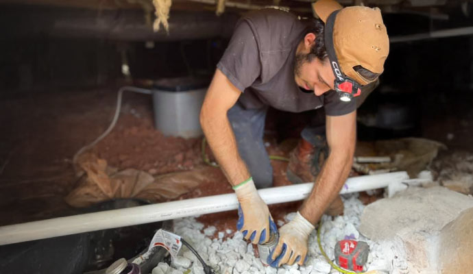 Professional repairing a crawlspace